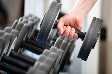 A hand lifting a dumbbell from a rack.