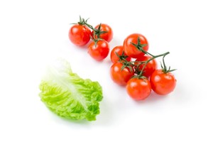 A bunch of tomatoes and a lettuce leaf on a white background.