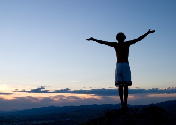 Arms outstretched on a sunset mountain.