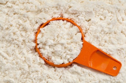 A large pile of protein powder with an orange scoop.