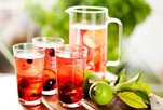 A jug and three glasses of berry infused lemonade on an outdoor table.
