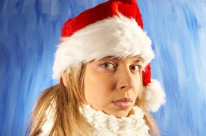 A women in a Christmas hat with a sad look on her face.