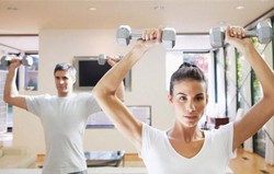 A man and a woman training in the gym.