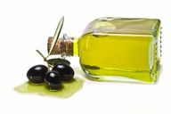 3 olives next to a glass bottle of olive oil.