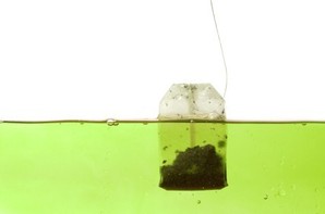 A bag of green tea in hot water.