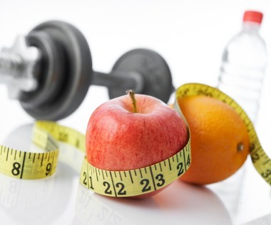 A dumbbell, tape measure, apple, orange and bottle of water.
