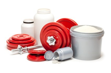 A collection of sports supplements next to a set of red dumbbells.