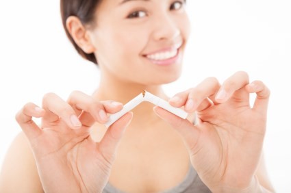 A smiling woman breaking a cigarette.