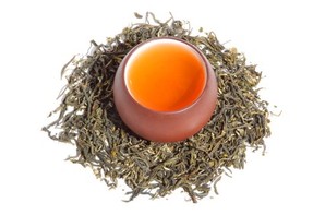 A cup of tea surrounded by tea leaves.