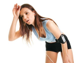 A woman exhausted from exercise wiping her brow.