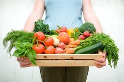 A woman holding a basket full of vegetables.