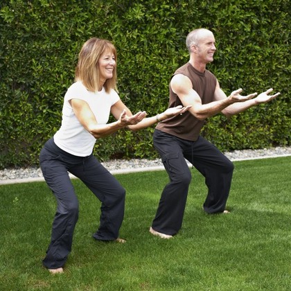 A man and a woman performing standing squats.