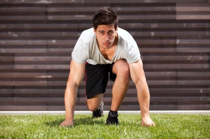A male runner crouching down, getting ready to sprint.