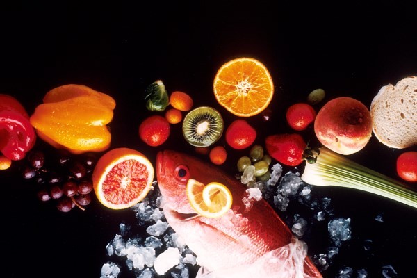 A selection of fish, fruits and vegetables on a black background.