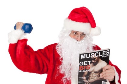Santa lifting a dumbbell and reading a muscle building magazine.