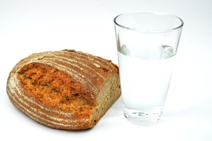A loaf of wholegrain bread next to a glass of water.