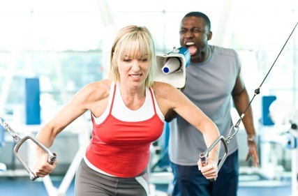 A girl working out while her personal trainer bellows instructions with a megaphone.