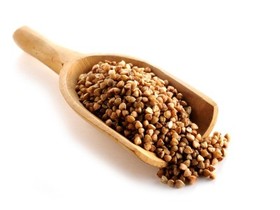 A wooden scoop full of buckwheat.