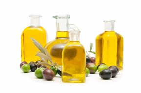 4 bottles of olive oil surrounded by olives.