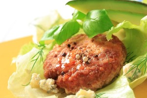 A lamb patty on a lettuce leaf with some blue cheese.