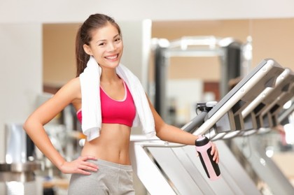 A woman in the gym standing by the exercise bikes.