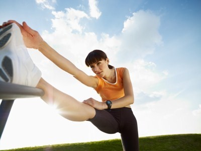 A woman stretching her right leg outside.
