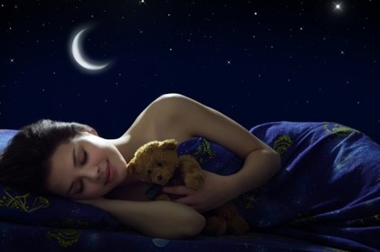 A girl sleeping with a teddy bear.