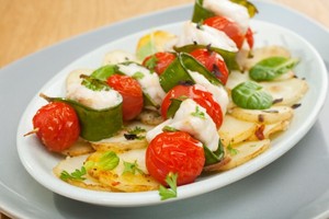 Monkfish and tomato kebabs on a white plate.