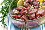 A bowl of lamb pieces in an olive oil and lemon marinade.