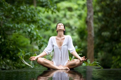 A woman doing yoga in a green forest.
