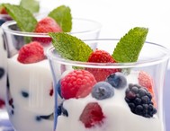 Two glasses of yogurt with a selection of berries.