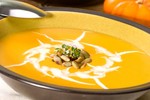 A bowl of creamy pumpkin soup topped with pumpkin seeds.