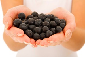 A woman holding a handful of blueberries.