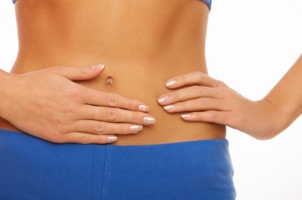 A woman with her hands placed over her abdominal muscles.
