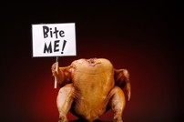 A cooked turkey holding a sign saying "Bite Me!"