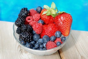 A bowl of assorted berries next to a pool.