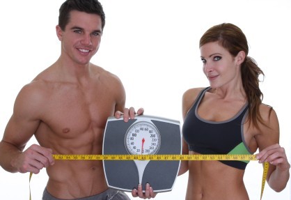 A healthy couple holding scales and a measuring tape.