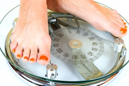 A close up of 2 feet on a pair of weighing scales.