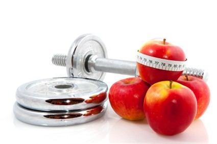 A set of dumbbells next to a pile of apples wrapped in a tape measure.