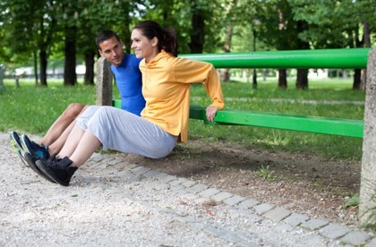 A couple performing dips outside.