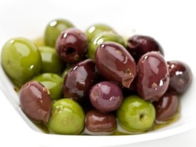 A plate full of black and green olives.