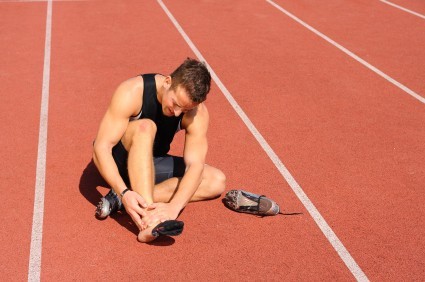 An injured runner sitting on a running track.