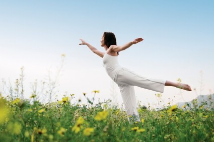 A woman practising yoga in a field.