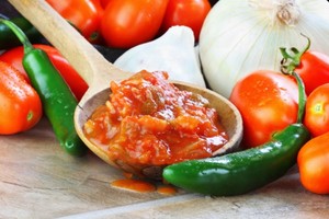 A spoon of home made salsa surrounded by the ingredients.
