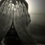 A man with both hands covering his face.