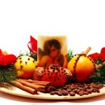 A plate containing a a candle, Christingles and nuts.