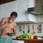 A man with toned abdominal muscles eating food in the kitchen.