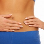 A woman with her hands placed over her abdominal muscles.