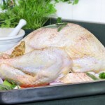 A raw turkey in a roasting tin with a selection of vegetables.