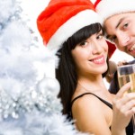 A couple in Christmas hats enjoying glasses of champagne.